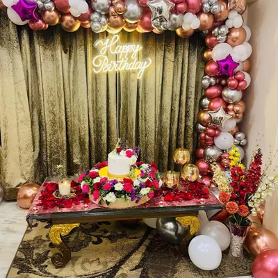 We also do birthday decor. This setup features a stunning balloon arch in shades of rose gold, pink, and silver, a "Happy Birthday" neon sign, and one of our floral cake platters as the centerpiece on the table.