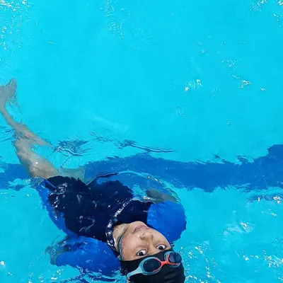 A young swimmer learning to float on his back, a key step in building water confidence in our beginner swimming lessons.