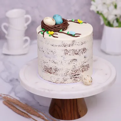 We welcome spring with this rustic and elegant Easter nest cake. A delicate chocolate nest with two speckled eggs sits atop a semi-naked cake, creating a simple yet beautiful centerpiece for your Easter celebration.