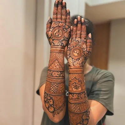 A beautiful, full-arm bridal design for an engagement ceremony. The design includes personalized initials and traditional motifs, covering the hands and forearms completely.