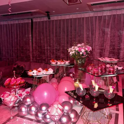 A sweet sixteen party deserves a spread that's both fun and fancy. This dessert and appetizer table is set amidst a sea of pink and silver balloons, featuring mocktails, macarons, and an array of bite-sized treats.