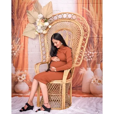 A serene solo portrait in our popular Boho setup. The large wicker peacock chair acts as a beautiful throne for the mom-to-be, and the earthy tones of her dress and the backdrop create a warm, natural feel.