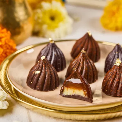 A close-up of our signature Modak Bonbons from the Ganpati menu. This one is filled with coconut-jaggery, capturing the traditional flavor in a modern chocolate shell.