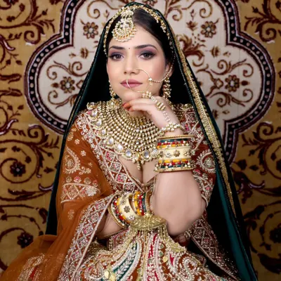 A truly regal look featuring a heavy, multi-layered Polki necklace paired with a wide choker, oversized jhumkas, a statement matha patti, and a delicate nath. This is for the bride who wants to make a grand entrance.