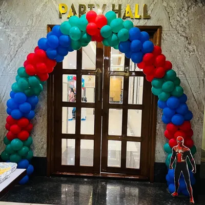 A classic balloon arch in superhero colors for the entrance to an Avengers-themed party hall.