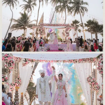A stunning beachside Hindu wedding ceremony, capturing the Varmala moment with colorful smoke in the background.