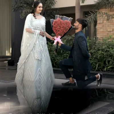 A classic proposal shot, with the groom on one knee presenting a heart-shaped bouquet to his bride-to-be in her beautiful gown.