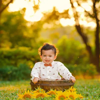 A beautiful golden hour portrait of a toddler in a rustic barrel surrounded by sunflowers. The warm, soft sunlight creates a magical glow, perfect for outdoor kids photography.