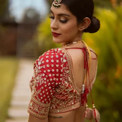 A truly royal bridal look. The deep red lip and defined eyes perfectly complement the exquisite embroidery of the red lehenga and the traditional back details.