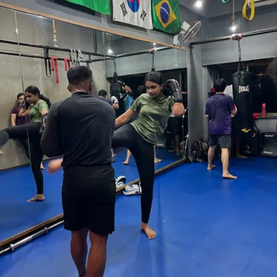 We focus on strength, speed, and precision in our kickboxing classes. Here, a student is perfecting her kicking technique during a one-on-one drill.