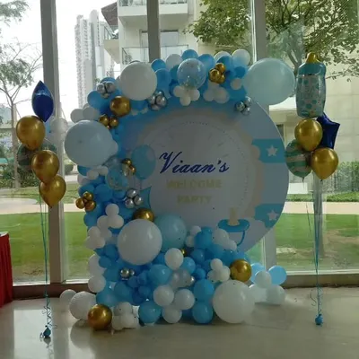 A classic and elegant welcome party setup for baby Vian. This decoration features a personalized circular backdrop with a blue, white, and gold organic balloon garland, perfect for celebrating a newborn boy.