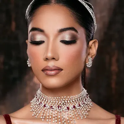 A moment of serene elegance. This bridal portrait focuses on the intricate diamond and ruby choker and the soft, shimmering eye makeup. The closed eyes and gentle pose create a feeling of peaceful anticipation.