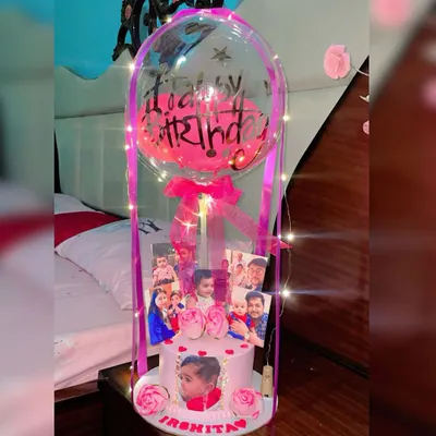 This is my signature balloon cake bouquet, perfect for making a big impression. For this order, I created a custom pink eggless cake featuring the birthday girl's photo, surrounded by a collage of family pictures. The entire display is wrapped in fairy lights and topped with a personalized "Happy Birthday" balloon.