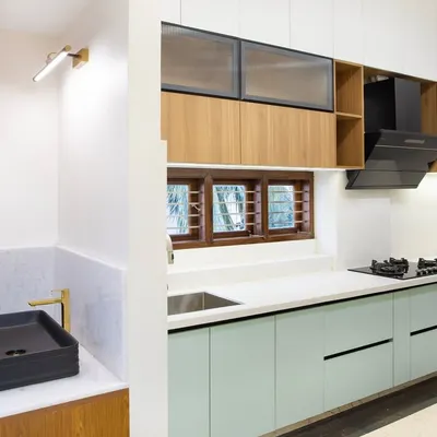 A view from the side, showing the main L-shaped kitchen workspace. The combination of matte sage green lower cabinets and wood-look uppers with fluted glass creates a soft, layered look that is full of texture and interest.