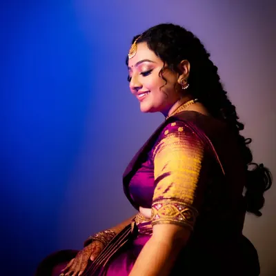 A creative bridal portrait using a mix of blue and purple light. The vibrant colors and her serene, smiling profile create a dreamy and artistic image.