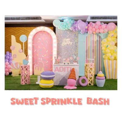 Welcome to the 'Sweet Sprinkle Bash'. This wide view shows our Candyland theme, complete with a donut-sprinkled arch, giant macarons, and ice cream props, all in a delightful pastel palette.