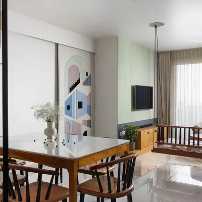This living area from 'The Pastel Abode' project showcases a gentle color palette of mint green, blush pink, and pastel blue. The artful sliding door, when open, reveals the bedroom corridor and acts as a unique design feature.