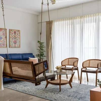 The living room in our 'Malhar' project is designed for connection, featuring a beautiful wood and cane swing that adds a playful, traditional touch. Paired with contemporary seating, it creates a balanced and inviting atmosphere for family and friends.