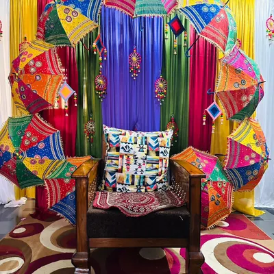 To bring a festive and colorful Rajasthani vibe to an event, I created this unique photo corner. An arch of vibrant, embroidered umbrellas provides a joyful and memorable backdrop for any celebration.
