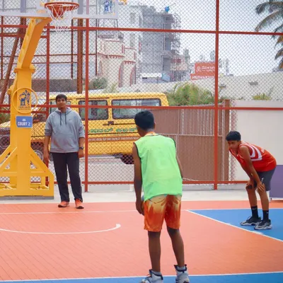 A view of a colorful outdoor basketball court during a junior league game. We offer access to courts with clear markings and sturdy hoops for an optimal playing experience.