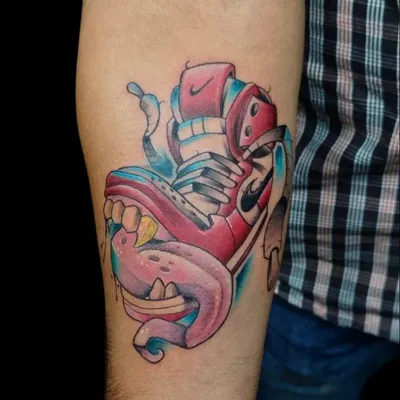A New School style tattoo of a sneaker with a monster mouth. This style is characterized by bold outlines, vivid colors, and exaggerated features.