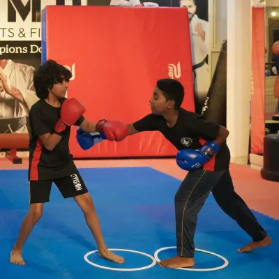 Young fighters learning the fundamentals of boxing, practicing their jabs and footwork within a controlled drill.