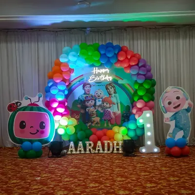 This Cocomelon themed stage is perfect for a first birthday party. The setup includes a full arch of rainbow balloons, large cutouts of the characters, a light-up number one, and a personalized backdrop to make the birthday child the star of the show.