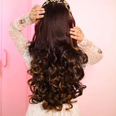 Hairstyle goals. This stunning open hairstyle features voluminous curls and a beautiful hair accessory, perfect for a reception or engagement.