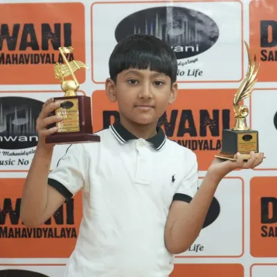 Double the joy! This young achiever proudly displays his two trophies from the Dhwani Kala Mahotsav, a result of his hard work in multiple disciplines.