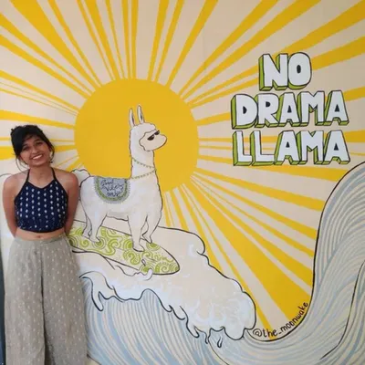 Standing proudly next to my 'No Drama Llama' mural, a piece that has become a landmark at the Royal Woods hostel in Goa. This shows the finished artwork in its environment, complete with a cool surfing llama and a sunny backdrop.