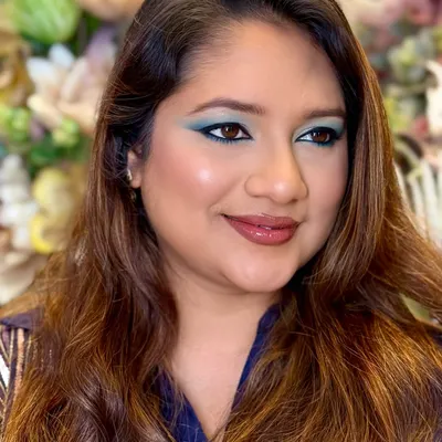 A side profile of a bold teal eyeshadow look. This angle highlights the seamless blending on the eyelid and the soft contouring on the cheek, creating a look that is all about confidence and character.