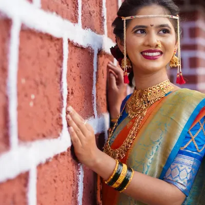 I love using different textures and backgrounds for bridal portraits. Here, the rustic red brick wall creates a beautiful contrast with the bride's elegant blue and orange saree and traditional gold jewellery, making the colors pop.