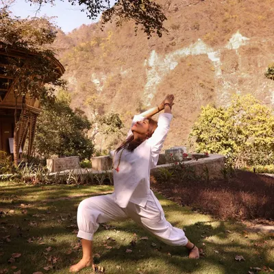 Practicing Virabhadrasana I, the warrior pose, surrounded by the serene energy of the Himalayas. My retreats are an invitation to find your inner strength and stand with grace, grounded in the beauty of nature.