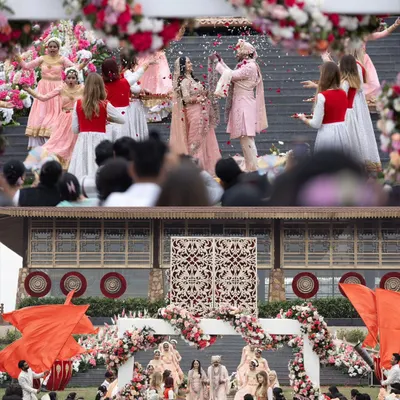 A grand view of Anisha and Rishabh's wedding ceremony, with dancers and guests creating a vibrant and festive atmosphere. This shot captures the scale and theatricality of a large Indian wedding.