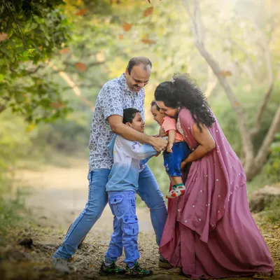 A family of four is captured in a moment of pure, chaotic joy on a rustic path, surrounded by trees. This image perfectly represents the lively and unposed nature of my outdoor family photoshoots.
