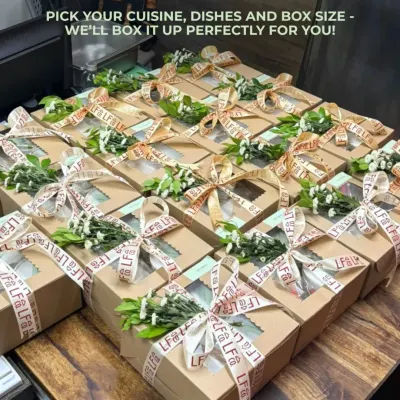 I can create beautifully customized boxes for any occasion. This image shows a large order of party boxes, each tied with a ribbon and a sprig of fresh flowers, ready for a special celebration. You pick the cuisine, dishes, and box size, and I'll handle the rest.