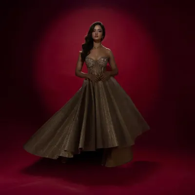 Designed for actress Shanvi Srivastava, this shimmering gold gown features a structured corset and a dramatic, high-low asymmetrical skirt. It's a high-fashion look, perfect for a red carpet event or a glamorous reception.