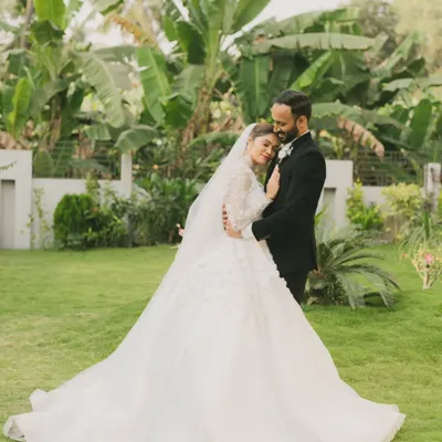 A quiet moment of connection in a lush garden setting. The bride's magnificent gown and the groom's classic suit create a timeless portrait of love and elegance.