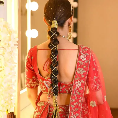 This is a modern take on a traditional bridal braid, also known as a parandi. I created an intricate bubble braid woven with golden thread and accented with tiny pearls for a Sangeet or wedding look.