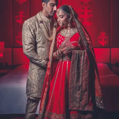 A regal portrait of a couple in a room bathed in red light. This kind of color and mood-setting is a signature of our cinematic style.