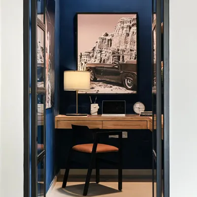This small nook was transformed into a moody and functional home office. I added see-through glass and black metal doors for privacy without closing off the space. The deep blue walls and oversized artwork create a cool, inspiring backdrop for video calls.