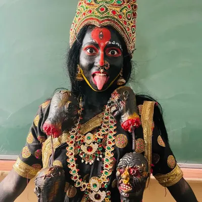 The complete Goddess Kali look, ready for the stage. The combination of intense black body paint, striking red and white details, and traditional costuming creates a truly memorable character.