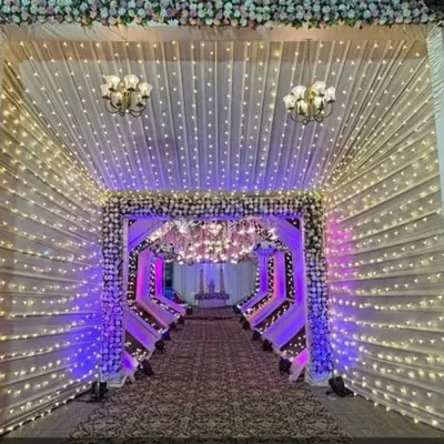 This illuminated tunnel is one of my signature entrance designs. The combination of fairy lights, draped fabric, and floral details creates a grand and magical pathway for your guests.