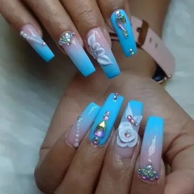 An extravagant display of 3D artistry on long, coffin-shaped extensions. This set features a blue ombré base, adorned with hand-sculpted white flowers, pearls, and a variety of iridescent rhinestones for a truly show-stopping look.