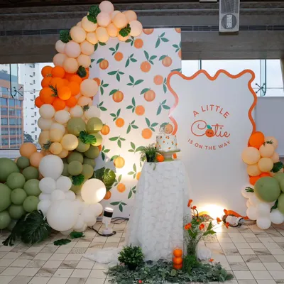 "A Little Cutie is on the way!" This vibrant backdrop, featuring a custom arch, orange-print wallpaper, and a cascade of citrus-toned balloons, was the cheerful centerpiece for a modern baby shower.