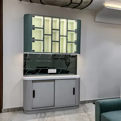 This contemporary crockery unit features a unique fluted design in a soft sage green. The upper cabinet has geometric glass panels and internal lighting, while the lower unit offers discreet storage with sliding doors.