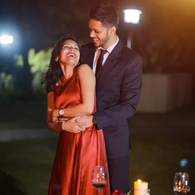 A romantic pre-wedding portrait session at night. The candlelight and warm lighting create an intimate and cozy atmosphere for this candid, laughing moment.