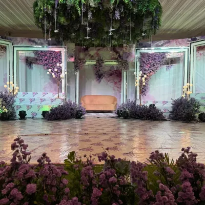 This reception stage is a dream in lavender. The design features a soft, romantic color palette, hanging floral installations, and modern lighting to create a whimsical and elegant atmosphere.
