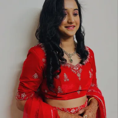 A happy client showing off her finished reception look. The soft curls frame her face beautifully, and the makeup is rosy and radiant, perfect for an evening party.
