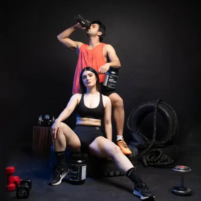 This is a hero shot from a lifestyle product shoot for a fitness supplement brand. We used two models to showcase the product's appeal to both men and women, creating a powerful image for website banners and social media campaigns. The dramatic studio lighting and gym-themed props establish an authentic, high-energy atmosphere.